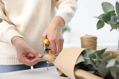 Çiçekçinin beyaz mermer masasında okaliptüs dallarından güzel bir buket yapıyor.