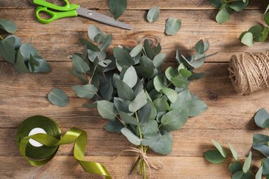 Çiçekçi. Okaliptüs dalları, iplik, kurdele ve makas ahşap masa, düz yatıyordu.