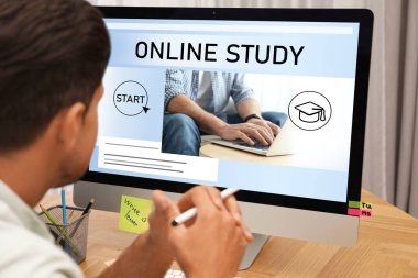 Çevrimiçi çalışma. Masada e-öğrenim için bilgisayarı kullanan adam, yakın plan