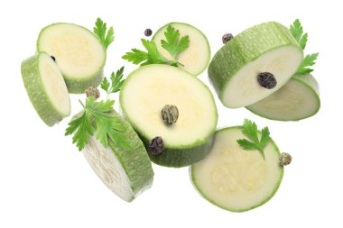 Taze kabak dilimleri, maydanoz ve beyaz arka plana düşen biberler.