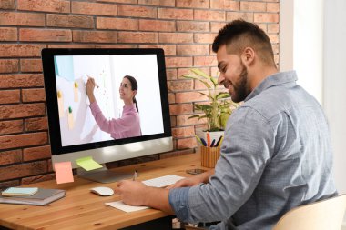 E-öğrenme konsepti. Öğrenci masadaki bilgisayar aracılığıyla öğretmenle çevrimiçi görüntülü sohbet ediyor