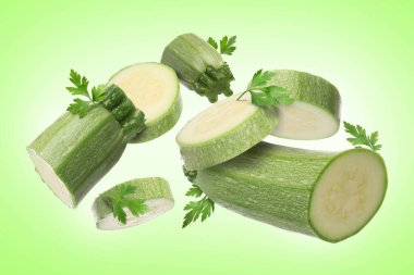 Taze kabak ve maydanoz parçaları açık yeşil arkaplana düşüyor.