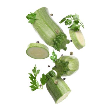 Beyaz arka plana düşen taze kabak, maydanoz ve biber parçaları.