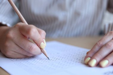 Öğrenci masadaki çoklu seçim testini dolduruyor, yakın çekim. Sınavı geçmek