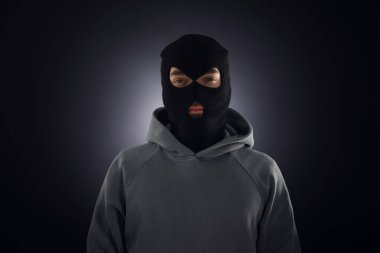 Karanlık arka planda maskeli bir suçlu.