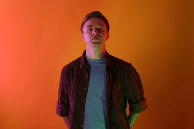 Turuncu arka planda neon ışıklı yakışıklı bir adam portresi.