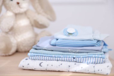 Temiz bebek kıyafetleri ve aksesuarlar ahşap masa içinde, yakın plan.