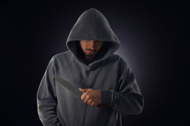 Kapüşonlu suçlu, siyah arka planda bıçak.