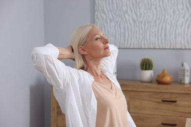 İş yerinde esneme hareketleri yapan güzel olgun bir kadın. Sağlıklı rahatlık.