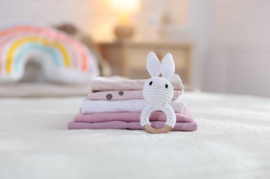Temiz bebek kıyafetleri ve yatak örtüleri iç mekanda, yakın plan.