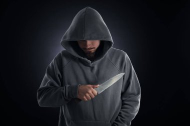 Kapüşonlu suçlu, siyah arka planda bıçak.