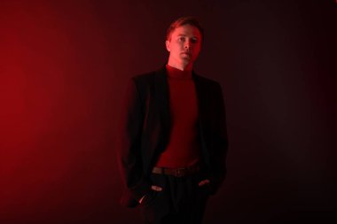 Siyah arka planda neon ışıklarda takım elbise giyen yakışıklı bir adamın portresi.