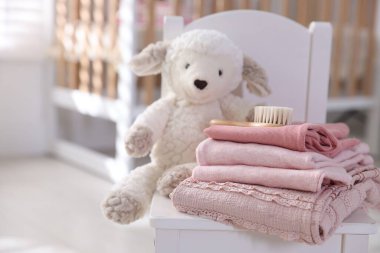 İçerideki küçük koltukta temiz bebek kıyafetleri ve aksesuarlar yığını, yakın plan. Metin için boşluk