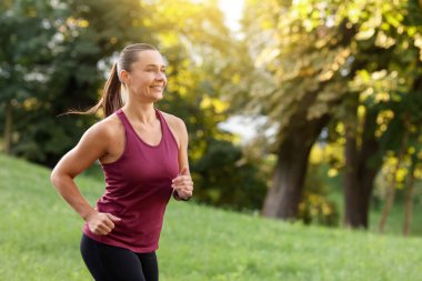 Spor giyim sektöründe atletik genç bir kadın açık havada koşuyor, mesaj için yer var.