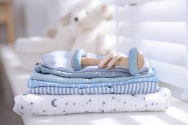 Temiz bebek kıyafetleri ve pencere pervazına aksesuar yığını.