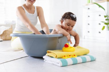 Anne küçük bebeğini evde yıkıyor, yakın plan.