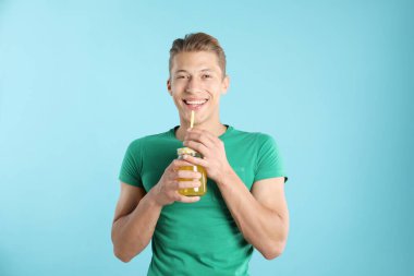 Meyve suyu ve açık mavi arka planda saman içen bir adam.