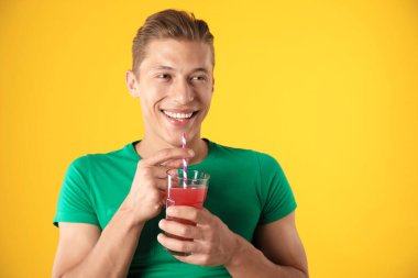 Meyve suyu ve turuncu arka planda saman içen adam.