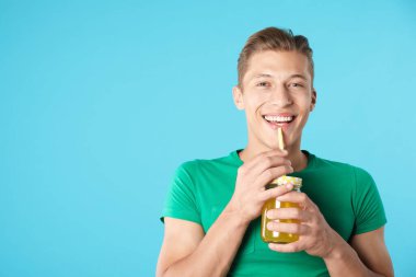 Meyve suyu ve açık mavi arka planda saman içen adam, metin için boşluk