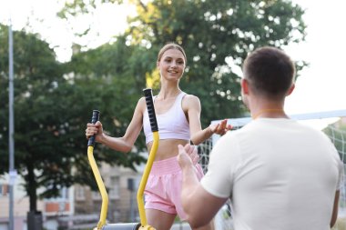 Genç adam dışarıda spor aletleriyle spor yapıyor. Profesyonel özel antrenörle dışarıda.