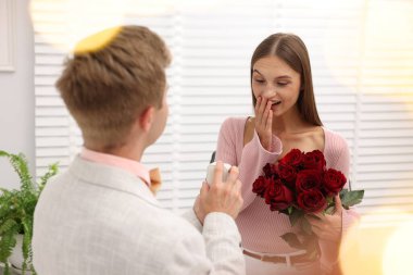 Nişan yüzüğü ve gül buketi olan bir adam mutlu kız arkadaşına evlenme teklif ediyor. Bokeh etkisi