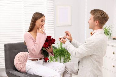 Nişan yüzüğü ve gül buketi olan bir adam mutlu kız arkadaşına evlenme teklif ediyor.