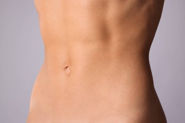 Gri arka planda düz göbekli kadın, yakın plan.