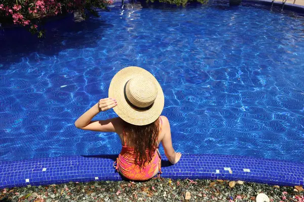 Güneşli bir günde havuz kenarında hasır şapkalı bir kız.