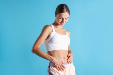 Açık mavi arka planda düz göbekli bir kadın.