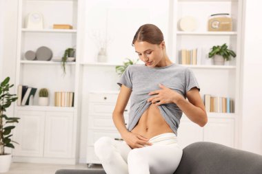 Evdeki koltukta karnı düz bir kadın, mesaj için yer var.