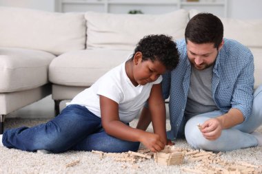Evlat edinme. Baba ve oğlu evlerinde tahta bloklarla oynuyorlar.