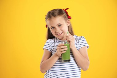 Meyve suyu ve turuncu arka planda saman içen küçük bir kız.