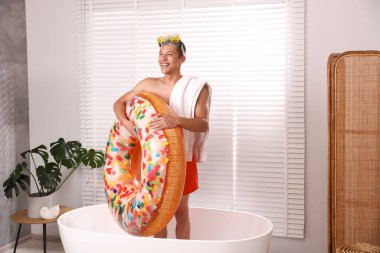 Şişme yüzüklü, dalış maskeli ve havlusuyla evdeki küvette mutlu bir adam. Denizde tatilin hayalini kuruyorum.