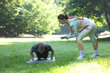 Genç adam profesyonel antrenörle dışarıda egzersiz yapıyor.