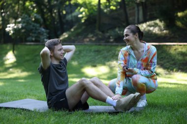 Genç adam profesyonel antrenörle dışarıda egzersiz yapıyor.