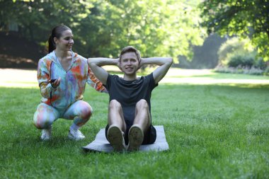 Genç adam dışarıda profesyonel antrenörle egzersiz yapıyor. Metin için boşluk