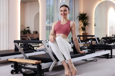 Pilates stüdyosunda yenilikçi bir kadın oturuyor.