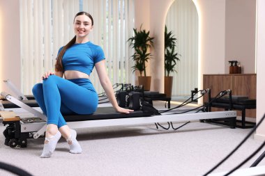 Pilates stüdyosunda yenilikçi bir kadın oturuyor.