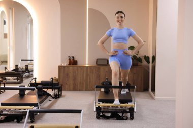 Pilates stüdyosunda reformist üzerinde egzersiz yapan bir kadın.
