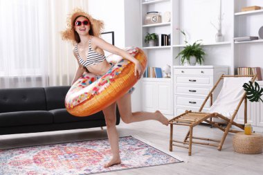 Güneş gözlüklü, hasır şapkalı, şişme yüzüklü mutlu kadın evde eğleniyor. Denizde tatilin hayalini kuruyorum.