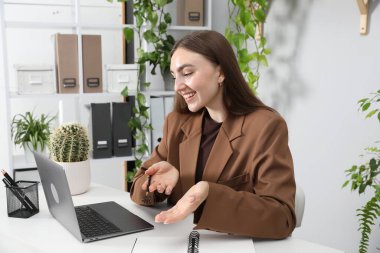 Ofiste bilgisayarla görüntülü konuşma yapan bir kadın.