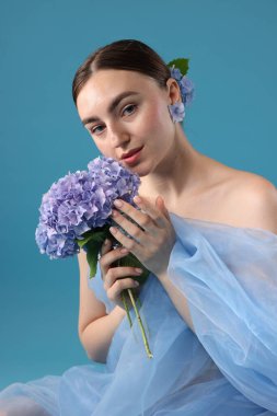 Güzel bir kadının portresi. Mavi arka planda çiçekli ve kumaşlı.