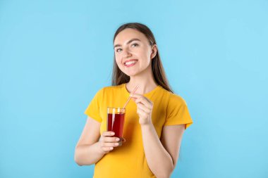 Serinletici bir içecek ve açık mavi arka planda saman taşıyan bir kadın.