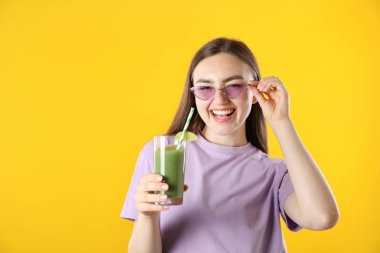 Turuncu arka planda canlandırıcı içecek ve pipetli kadın, metin için boşluk