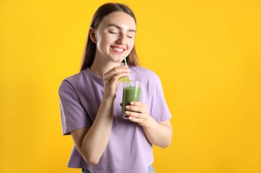 Turuncu arka planda serinletici içkisi ve pipetli kadın