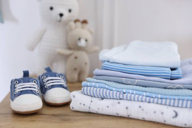 İçerideki ahşap masada temiz bebek kıyafetleri ve ayakkabılar yığını.