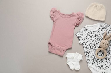 Gri arka planda şık bebek kıyafetleri ve aksesuarları, düz yatış. Metin için boşluk