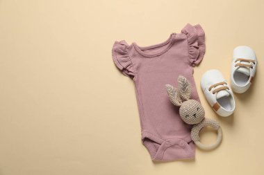 Bej arka planda şık bebek kıyafetleri ve aksesuarları, düz yatış. Metin için boşluk
