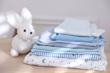 Temiz bebek kıyafetleri ve aksesuar yığını kapalı masa, yakın plan.