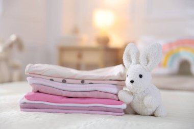 Temiz bebek kıyafetleri ve yatak örtüleri iç mekanda, yakın plan.